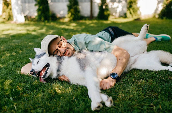Man lying in the grass with a husky